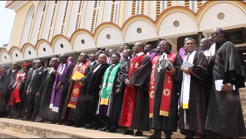 Clergy in gowns and coloured stoles gathered on the steps of a church